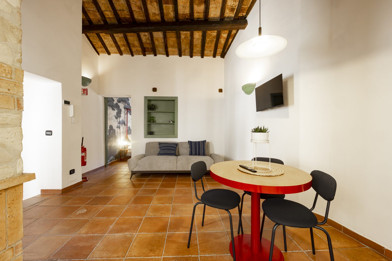 Zona living con soffitto in travi, tavolo tondo e divano grigio